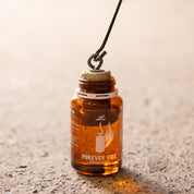 Feueranzünder: Brennkegel wird mithilfe des Hakens ins Öl gegeben