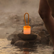 Floppy Silikonlaterne auf Steinen am Wasser in Sunset Orange